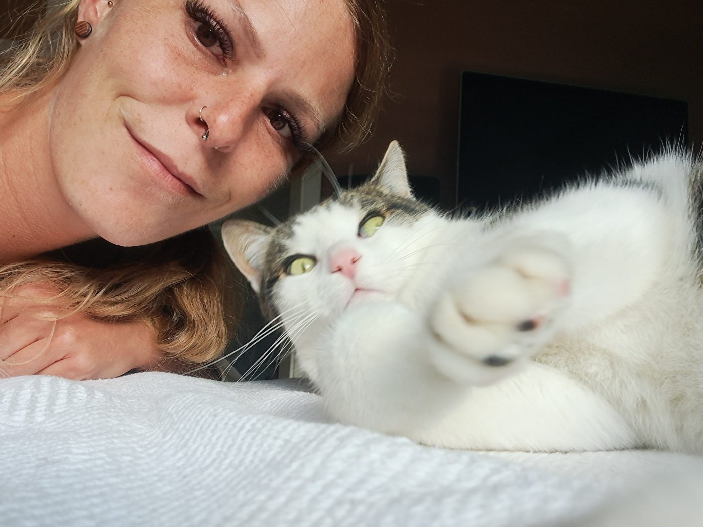 Auf dem Bild sieht man den Katzensitter, Saskia von Purrfect mobile Katzenbetreuung Berlin, zusammen mit einem Kater liegen